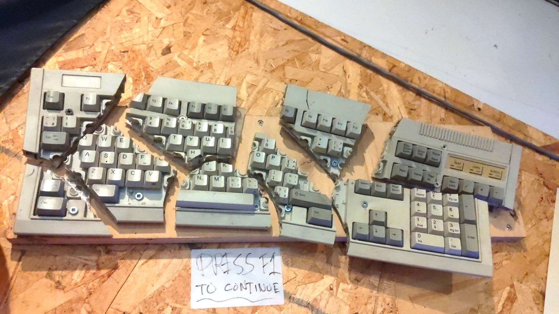 An exploded keyboard with a 'Press F1 to continue' sign