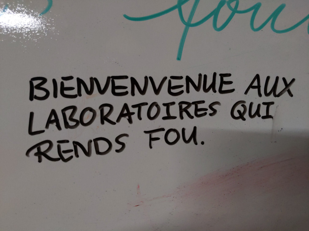 A sign on a whiteboard that says 'Bienvenue aux laboratoires qui rends fou'