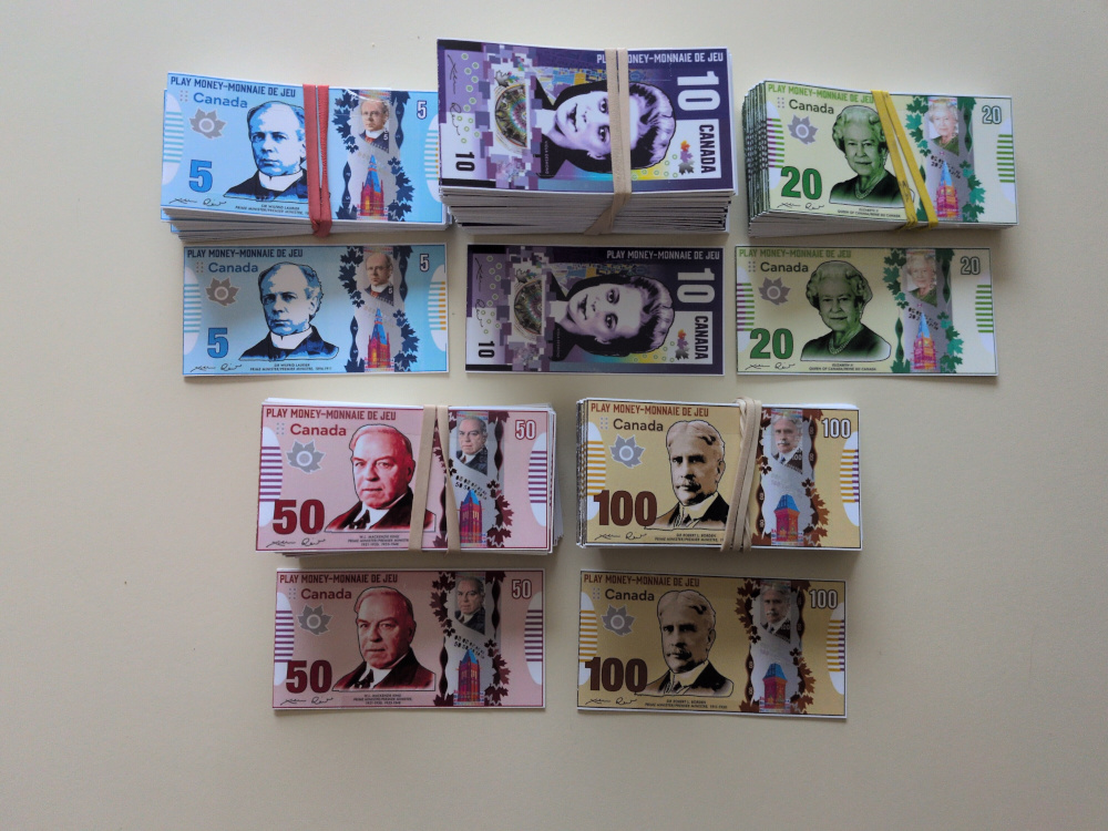 Stacks of play money bills, with examples of the 5$, 10$, 20$, 50$ and 100$ bills